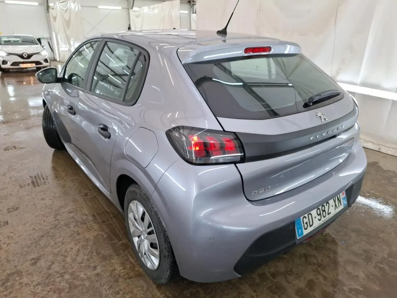 Vue 3/4 arrière droite d'une Peugeot 208 gris Artense avec feux arrière noirs et jantes tôles 15 pouces.