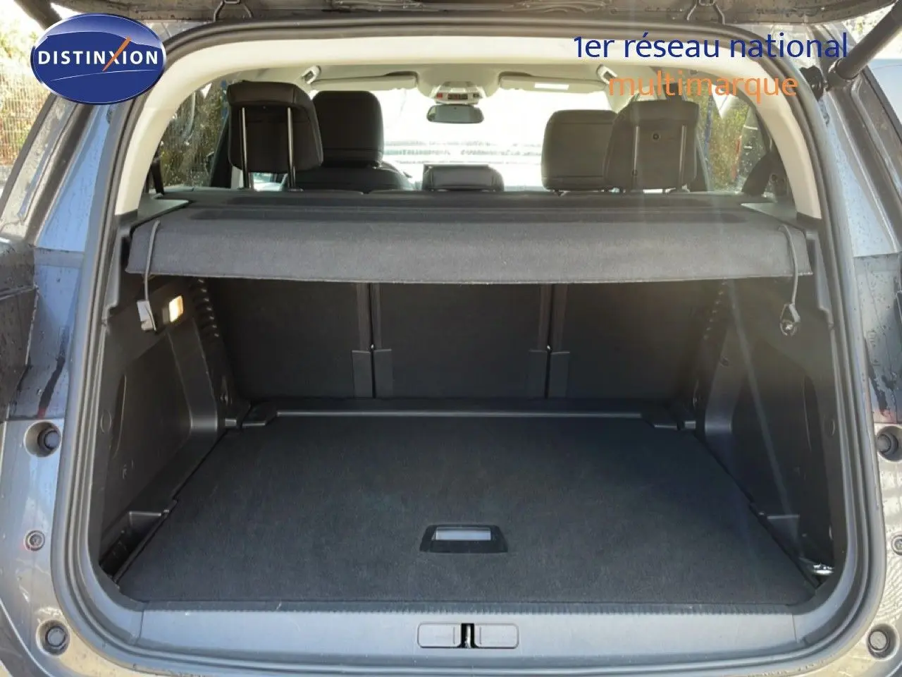 Coffre ouvert vu de l'arrière d'un Citroën C5 Aircross gris platinium métal avec cache-bagages en place.