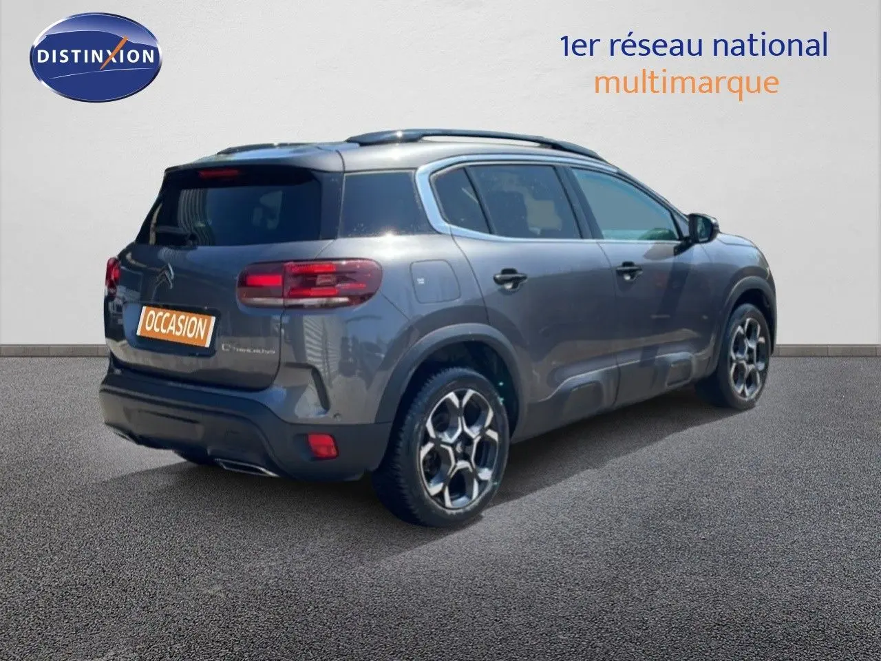 Vue 3/4 arrière droite d’un Citroën C5 Aircross gris platinium métal avec jantes bi-ton et toit ouvrant.
