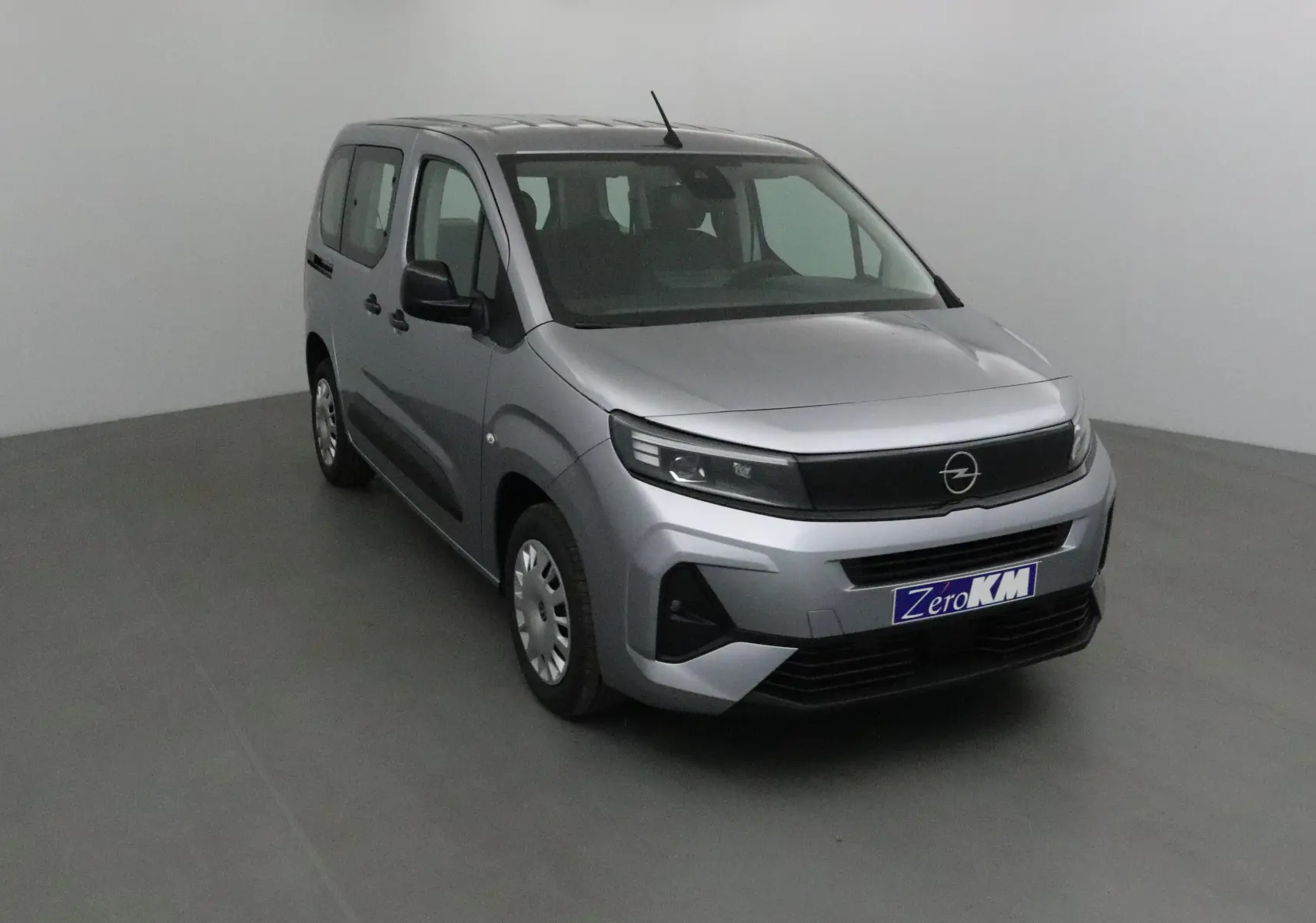 Opel Combo Life gris Artense vu en 3/4 avant droit, avec calandre noire et jantes acier simples.