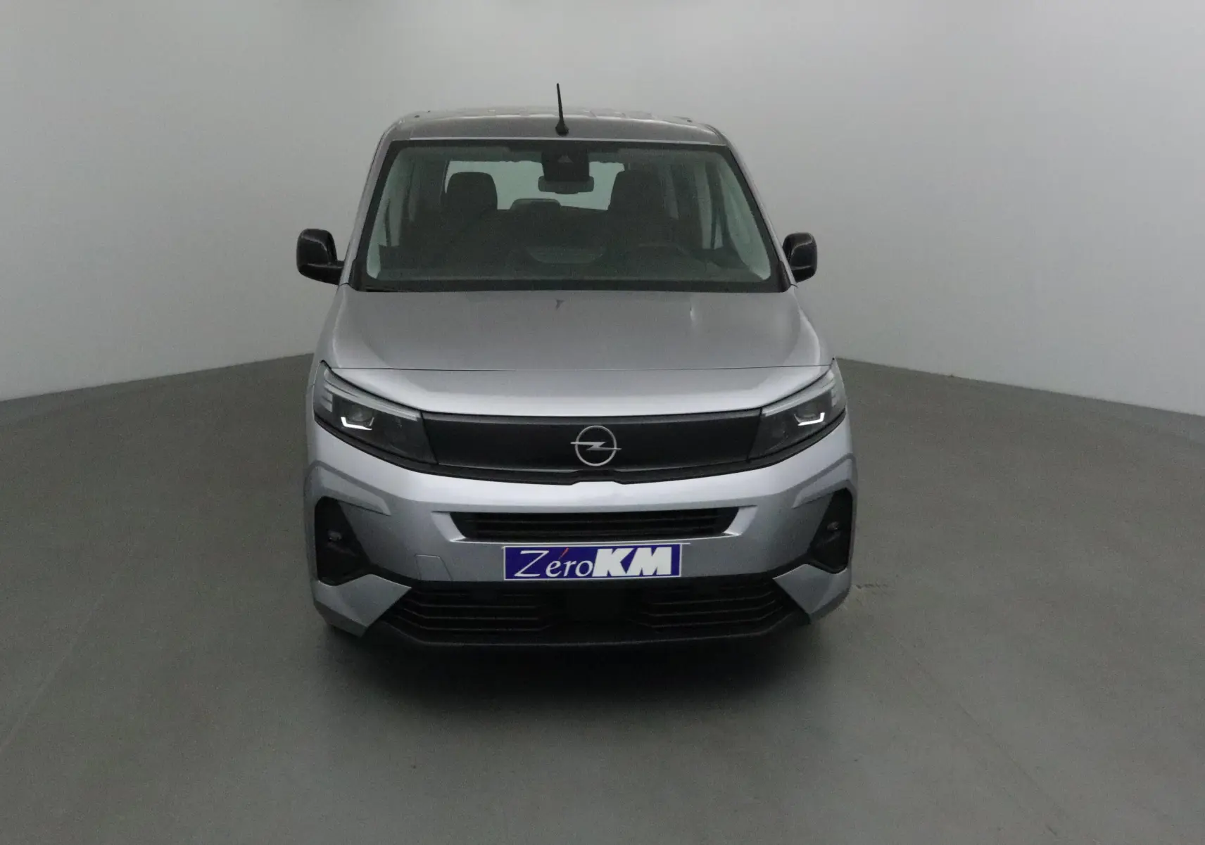 Vue frontale d'un Opel Combo Life gris Artense avec calandre noire et phares LED allumés dans un studio.