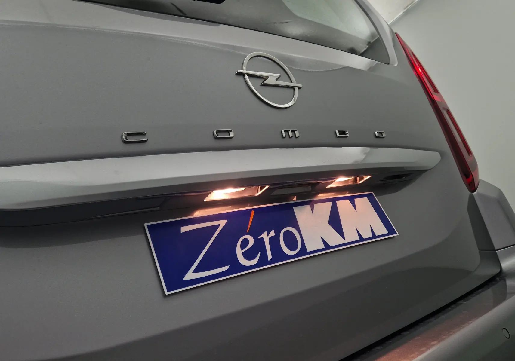 Gros plan sur l'arrière gris Artense de l'Opel Combo Life avec logo et plaque d'immatriculation éclairée Zero KM.
