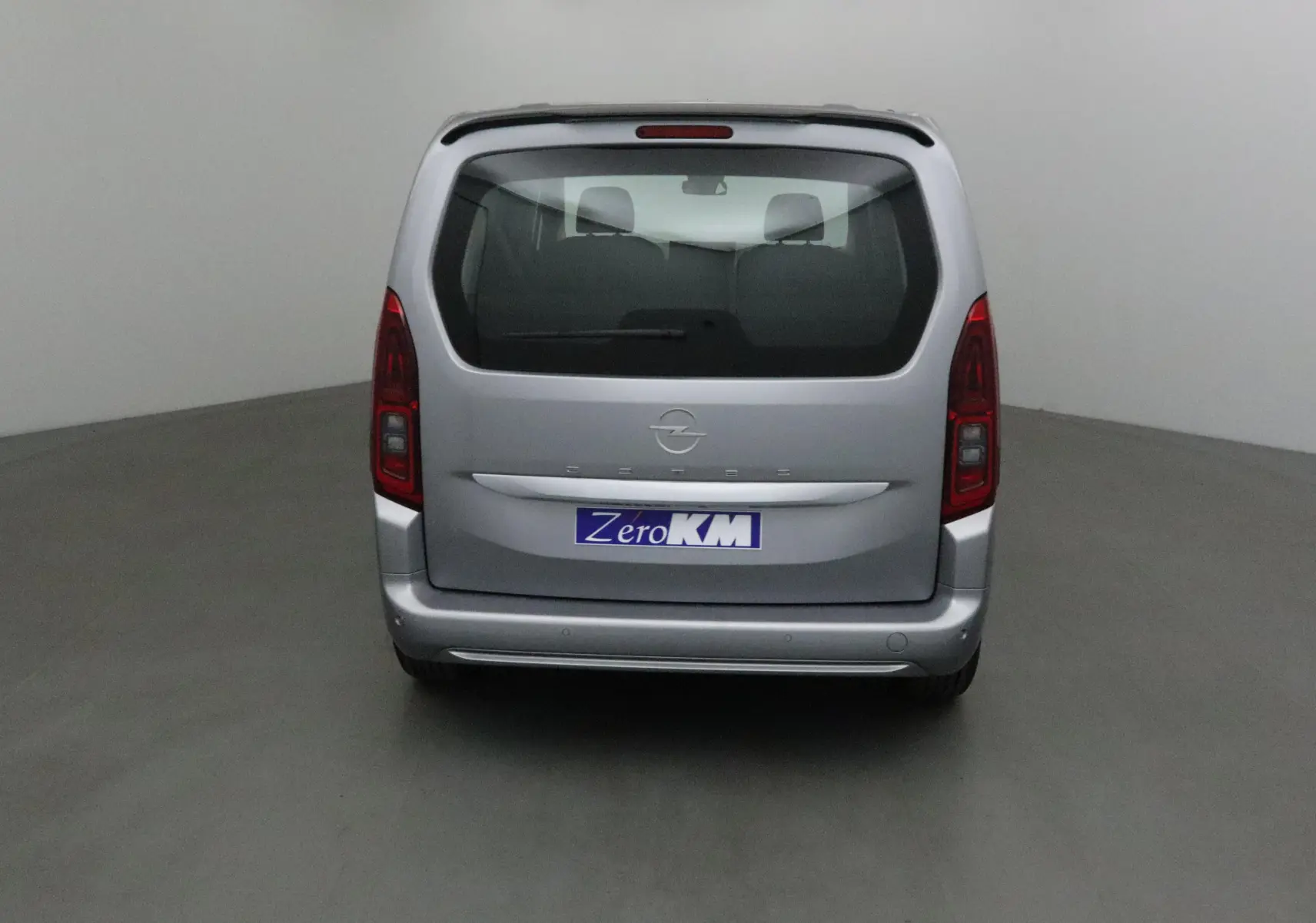 Vue arrière d'un Opel Combo Life gris Artense avec becquet et feux arrière verticaux dans un studio.