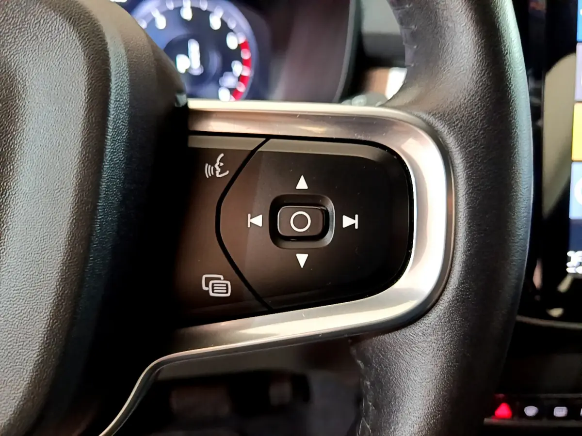 Gros plan sur les commandes multifonctions du volant en cuir noir du Volvo XC40 T2 gris clair, vue intérieure côté gauche.