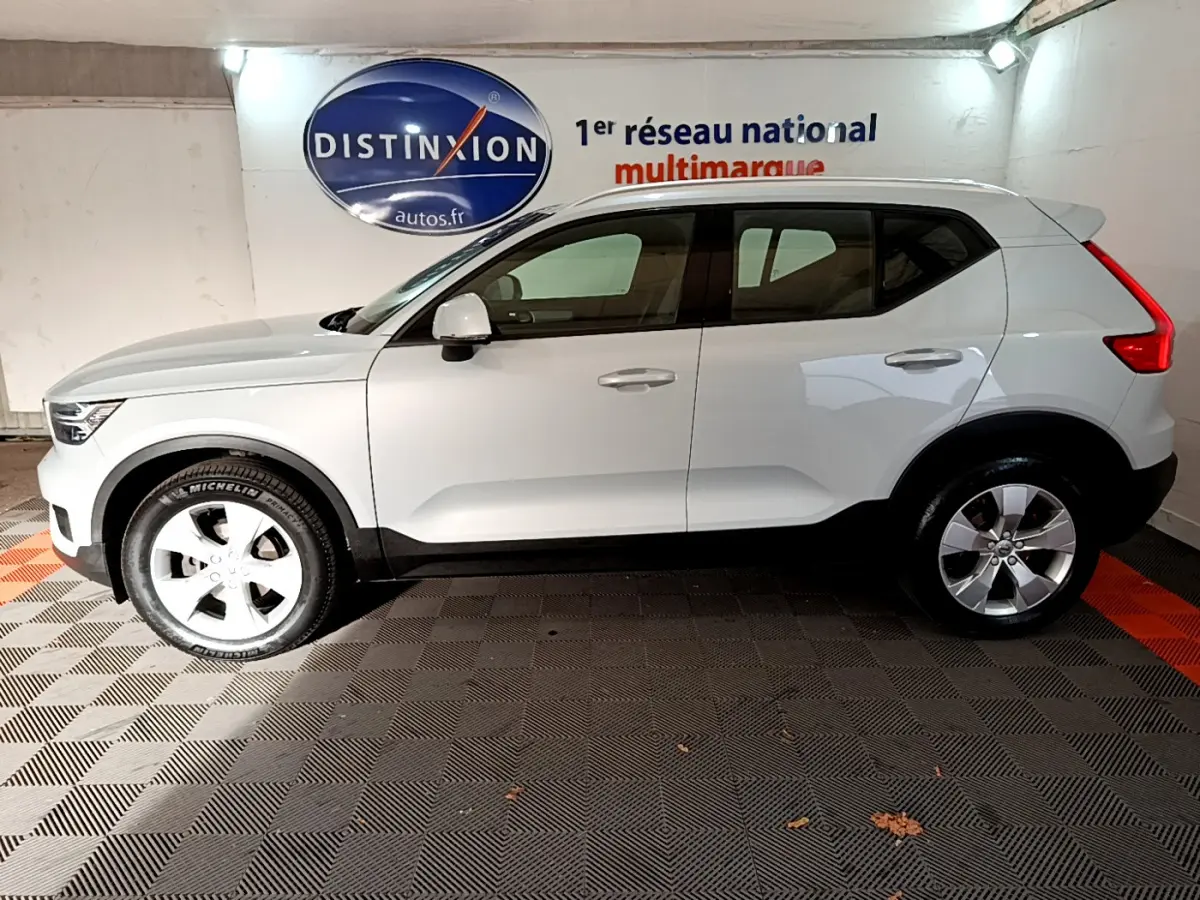 Vue latérale droite d'un Volvo XC40 gris clair garé en intérieur avec jantes alliage et toit blanc.