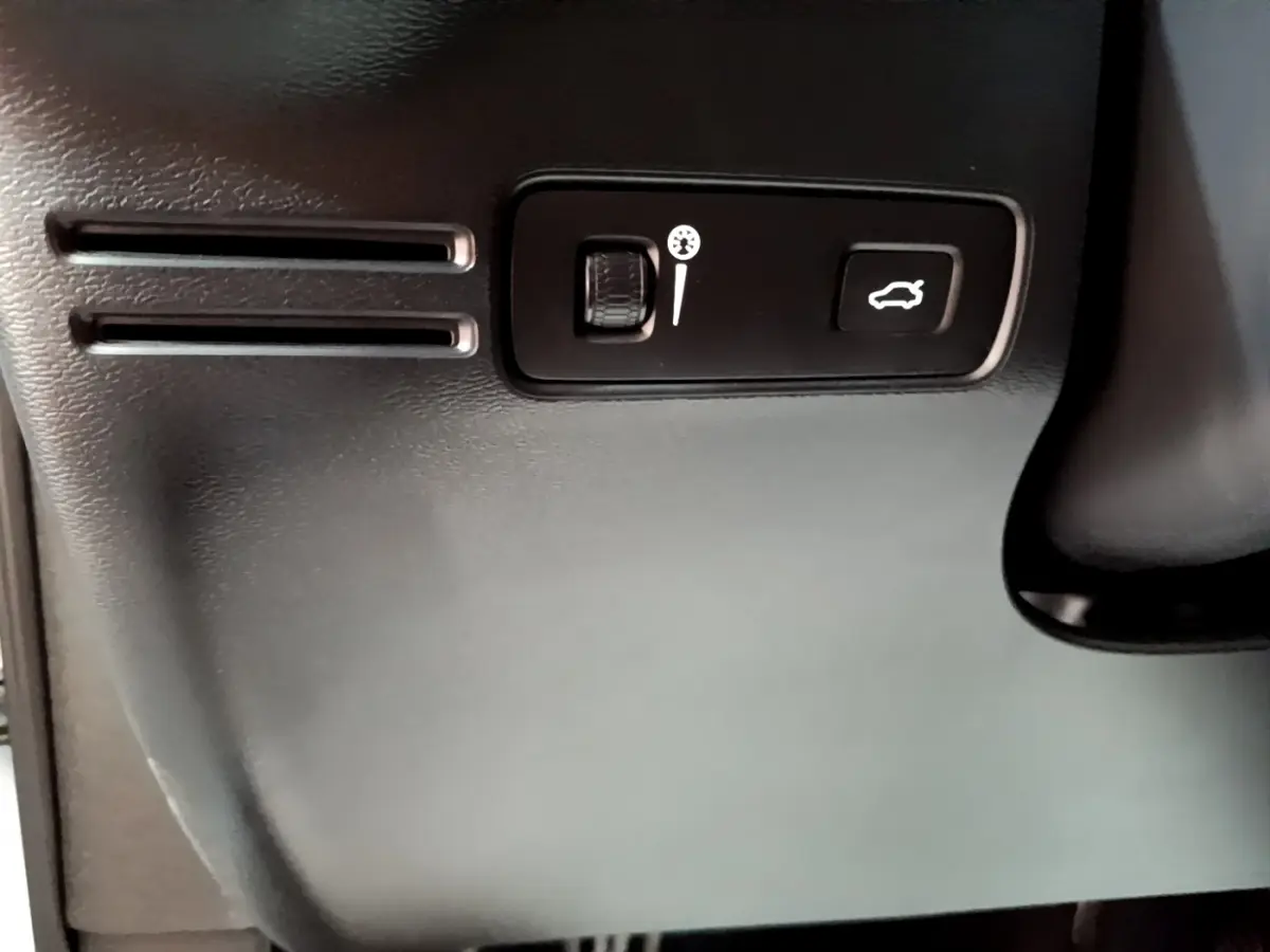 Détail intérieur montrant les commandes d'ouverture du coffre et réglage du volant sur Volvo XC40 T2 gris clair.
