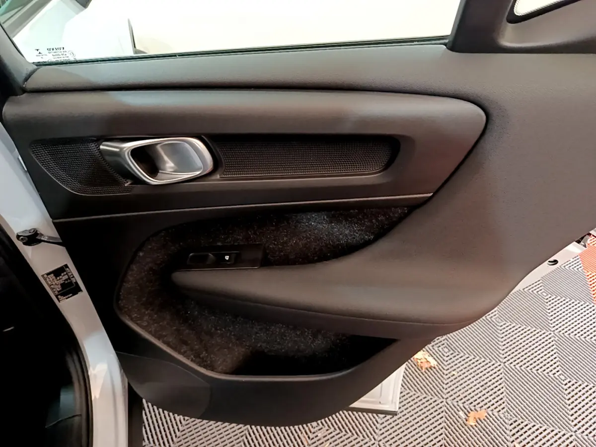 Vue intérieure de la porte arrière gauche grise du Volvo XC40 T2 Momentum avec poignée alu et commande de vitre.