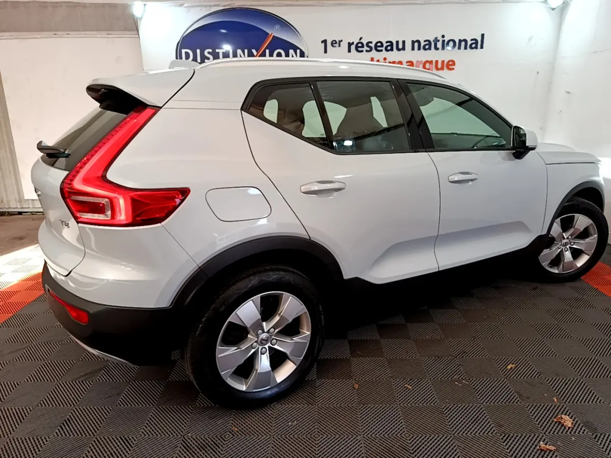 Vue 3/4 arrière droite d'un Volvo XC40 T2 gris clair avec feux arrière LED en forme de C et jantes alliage.