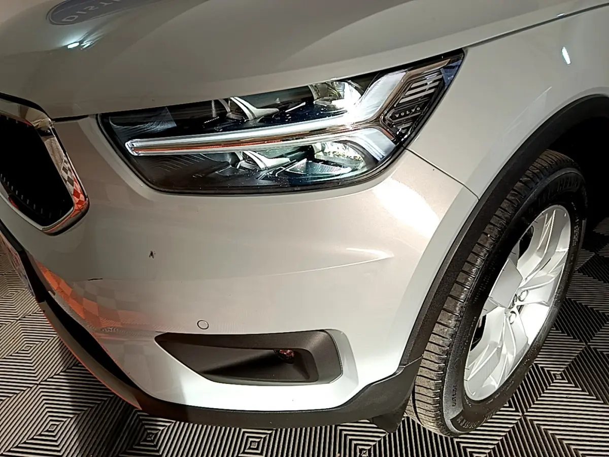 Gros plan sur l'avant droit gris clair du Volvo XC40 T2 129 Momentum, mettant en valeur le phare LED et la roue.