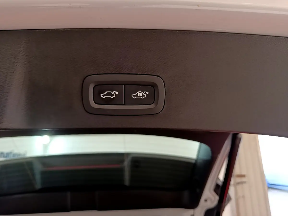 Gros plan sur les boutons d'ouverture et verrouillage du coffre, intérieur noir du hayon du Volvo XC40 gris clair.