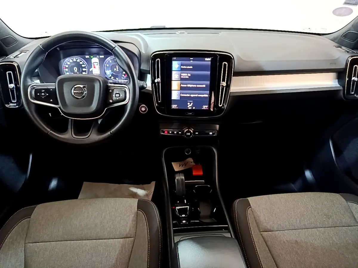 Vue intérieure avant du Volvo XC40 T2 Momentum 2020, tableau de bord noir avec écran tactile central et volant cuir multifonctions.