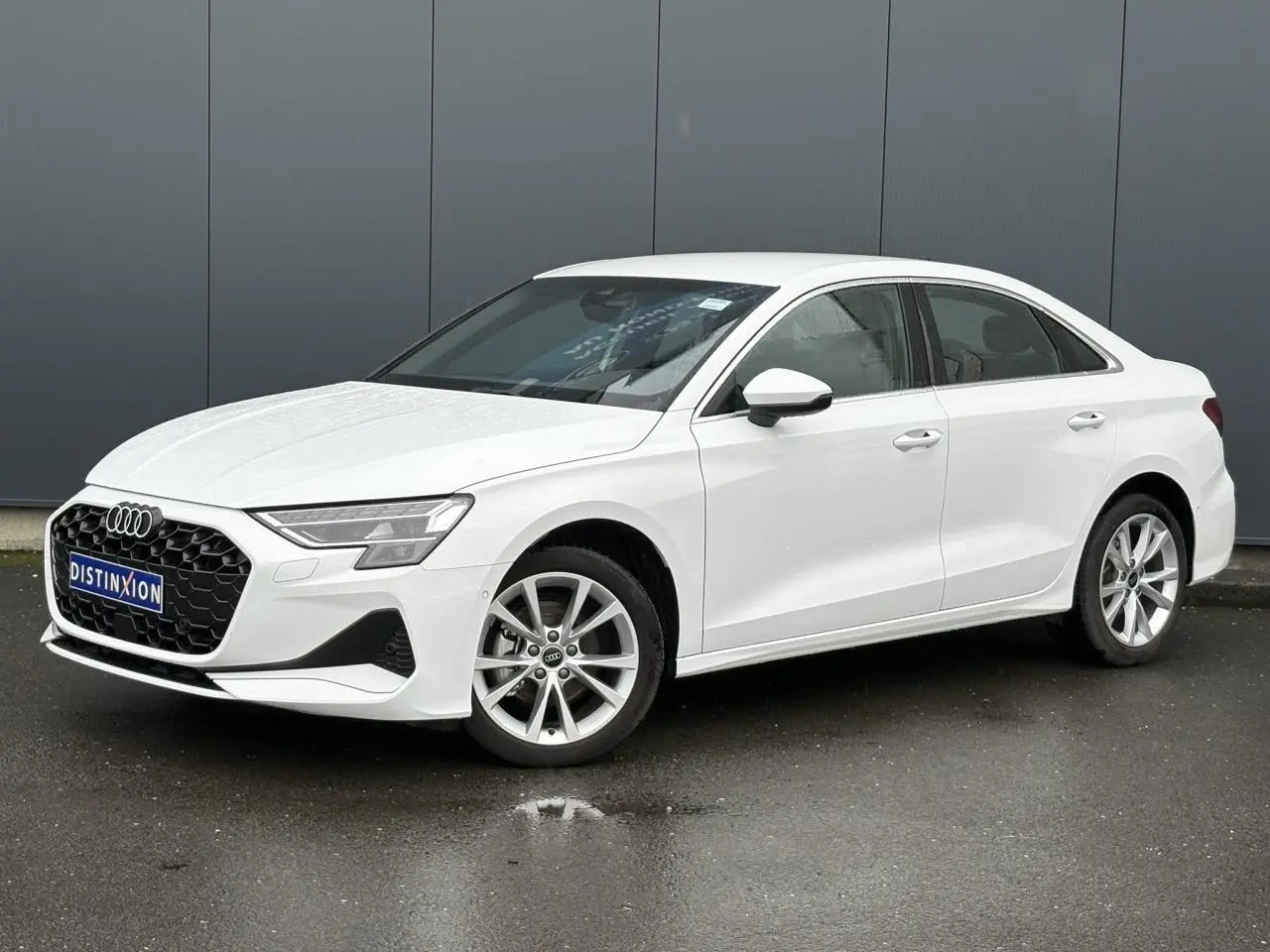 Audi A3 Berline blanc Arkona vue 3/4 avant droit, jantes alliage 17 pouces et calandre hexagonale noire.