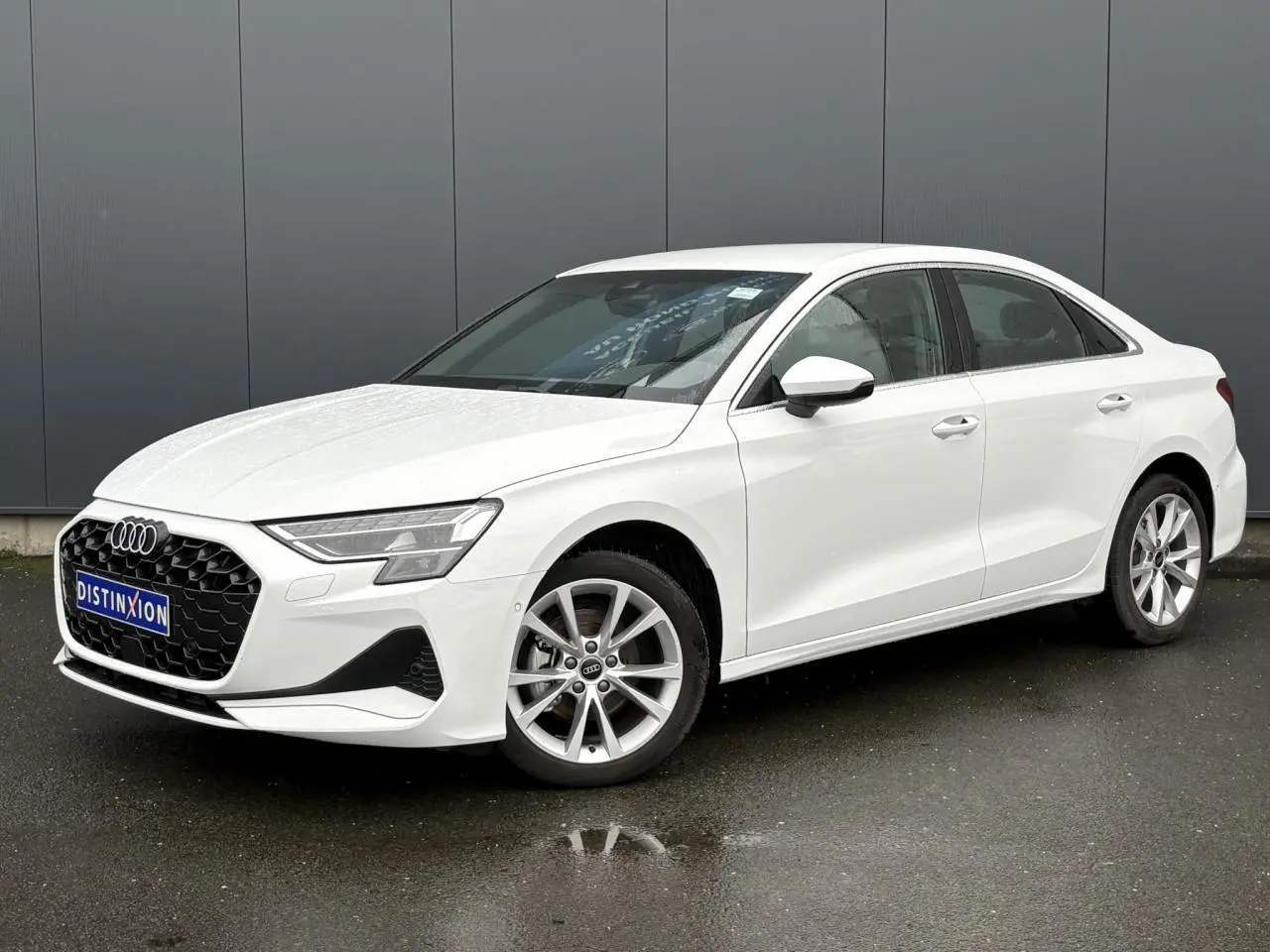 Audi A3 Berline blanc Arkona vue 3/4 avant droit, jantes alliage 17 pouces et calandre hexagonale noire.