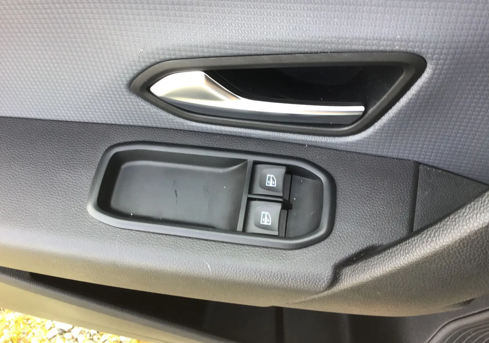 Gros plan sur la poignée intérieure et les commandes des vitres côté gauche d’un Renault Express Van blanc 2023.