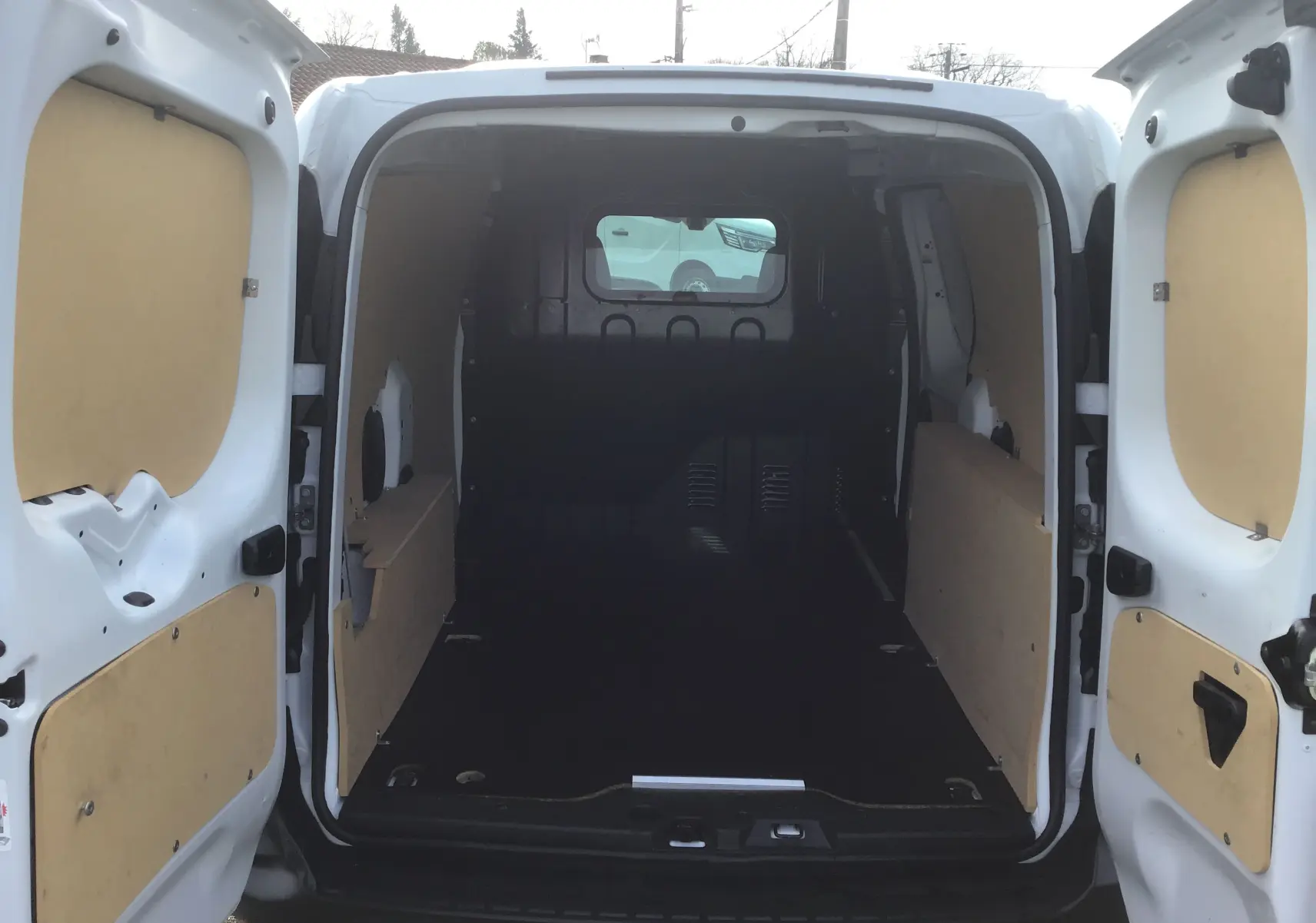 Vue arrière du Renault Express Van blanc 2023 avec portes ouvertes montrant l’espace de chargement vide et les panneaux en bois.
