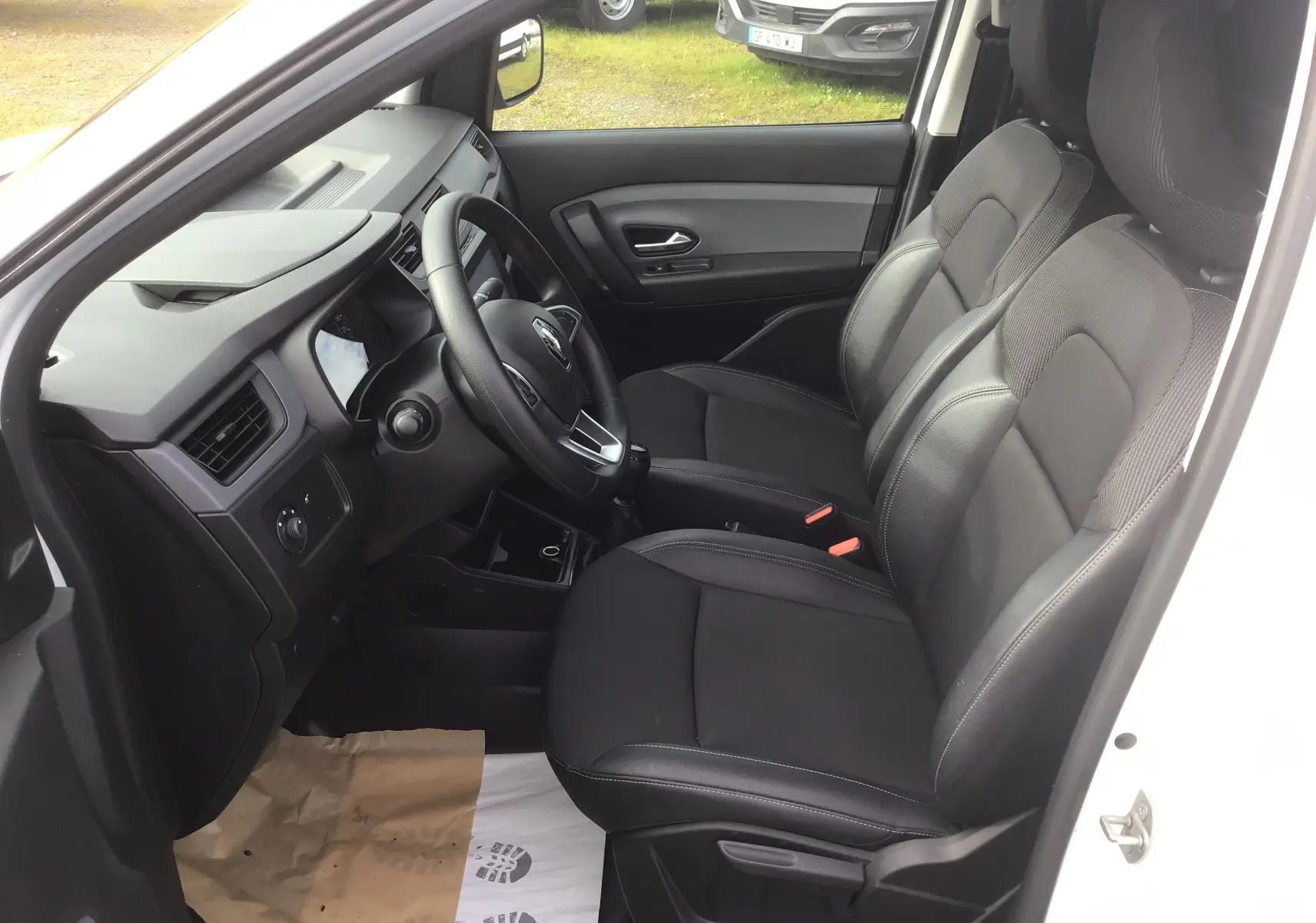 Vue intérieure côté conducteur du Renault Express Van blanc 2023, montrant les sièges noirs et le tableau de bord épuré.