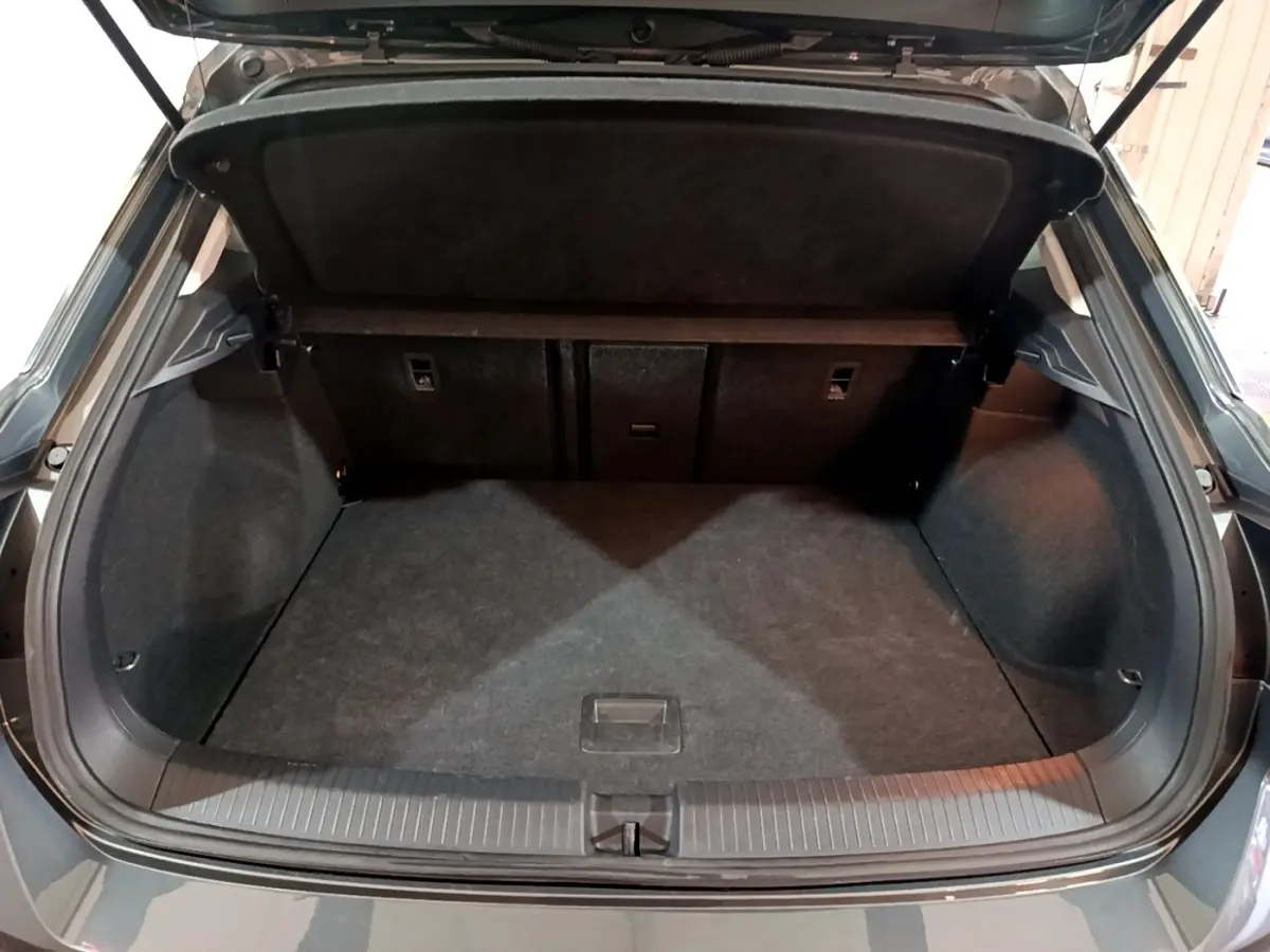 Vue arrière du coffre ouvert du Volkswagen T-ROC gris foncé, montrant un espace de chargement propre et spacieux.