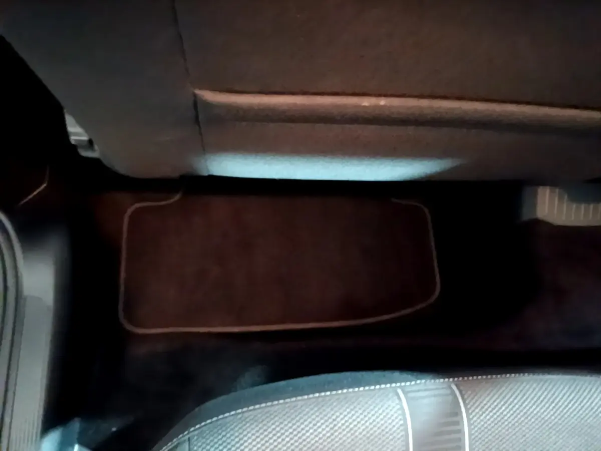 Vue intérieure du plancher arrière avec tapis de sol noir et partie inférieure du siège dans un Volkswagen T-Roc gris foncé.