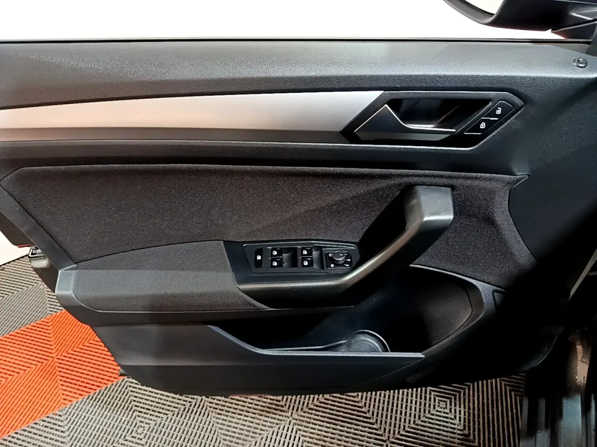 Vue intérieure côté gauche de la porte avant grise du Volkswagen T-Roc 2022 avec commandes de vitres et poignée noire.
