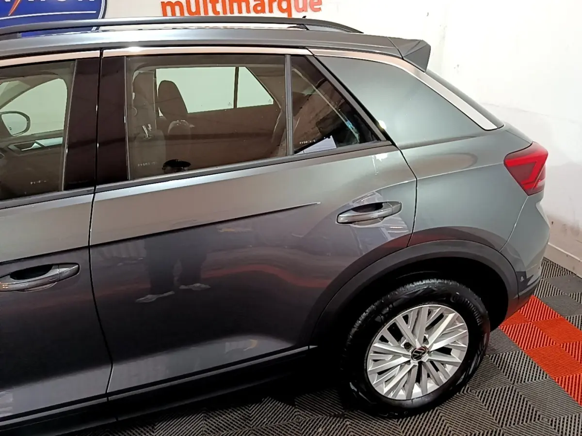 Vue latérale côté droit du Volkswagen T-Roc gris foncé, mettant en valeur la porte arrière et la roue arrière avec jante alliage.
