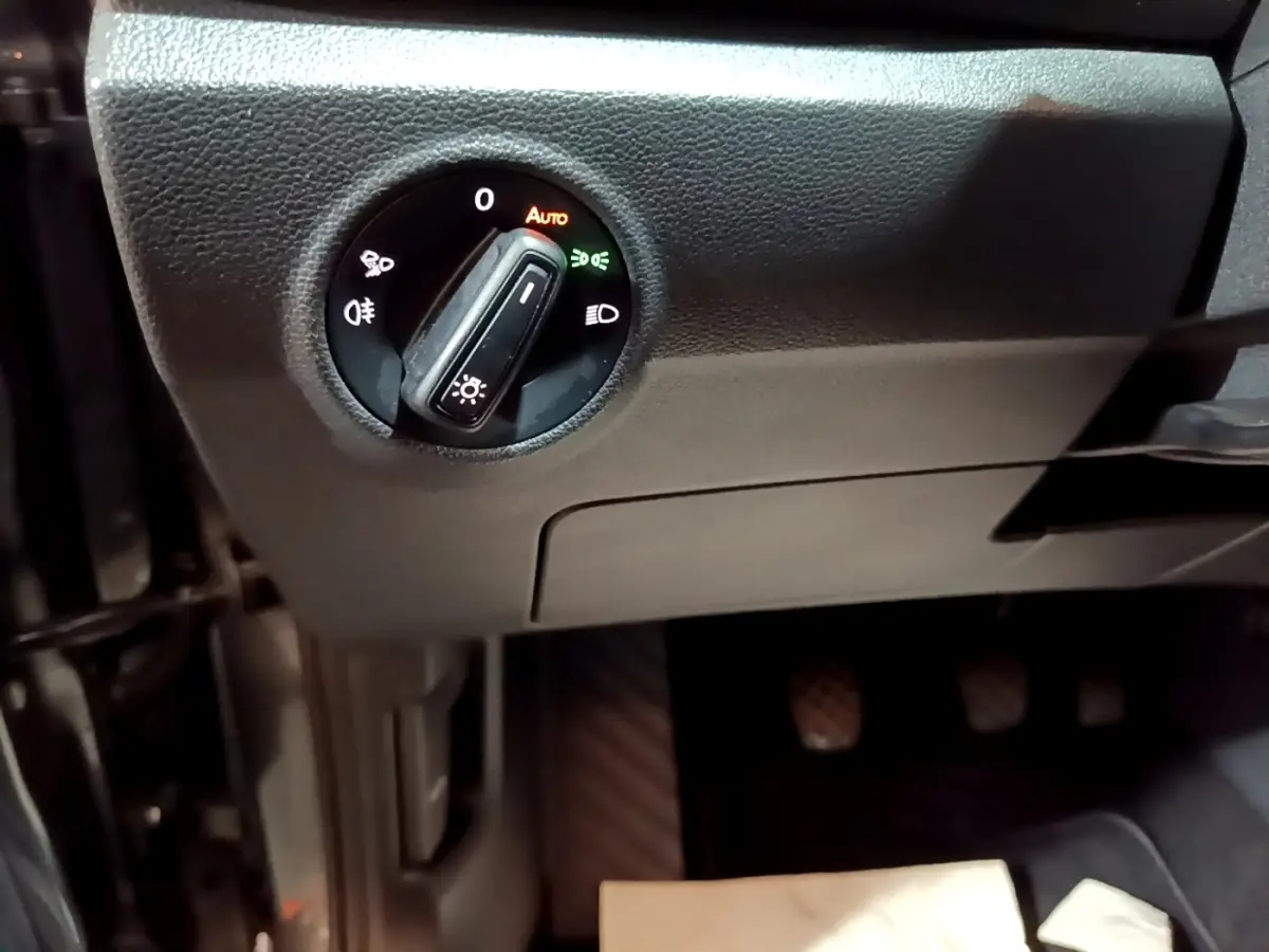 Gros plan sur le bouton de commande des phares dans l’habitacle noir du Volkswagen T-Roc 2022, côté conducteur.