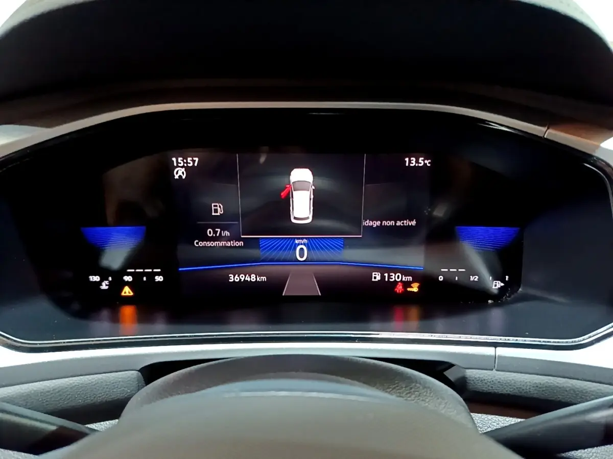 Vue rapprochée du tableau de bord numérique du Volkswagen T-Roc gris foncé, affichant la consommation et la distance restante.