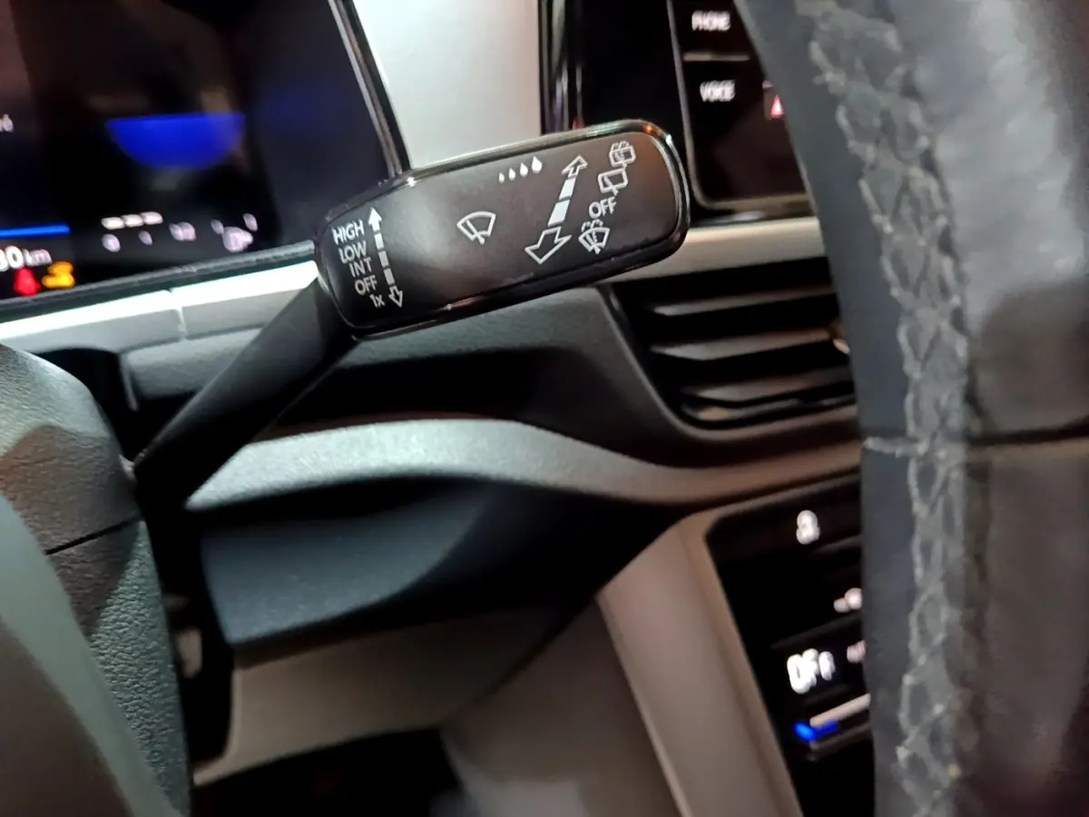 Gros plan sur la manette d’essuie-glace à gauche du volant cuir dans l’habitacle du Volkswagen T-Roc gris foncé.