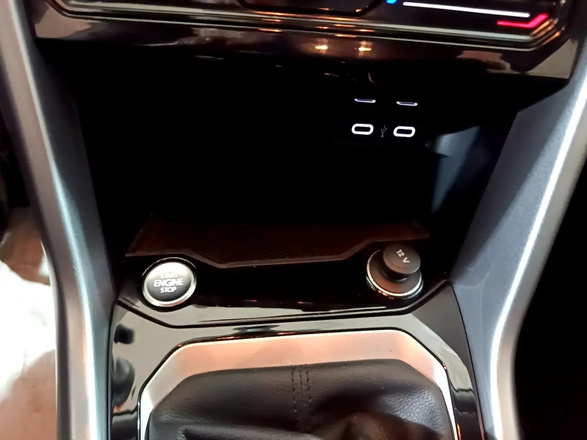 Gros plan sur la console centrale du Volkswagen T-Roc gris foncé, montrant bouton start/stop et prise 12V.