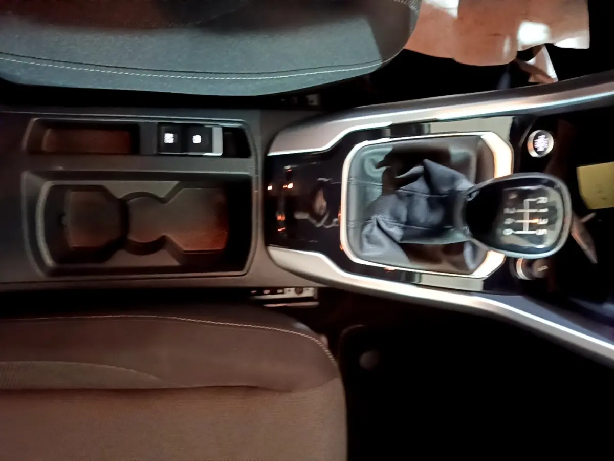 Vue plongeante sur la console centrale d’un Volkswagen T-Roc 2022 avec levier de vitesse manuel et rangement noir.