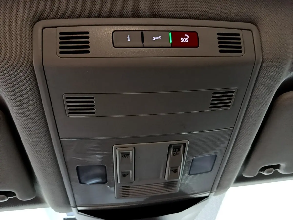 Vue en contre-plongée du panneau de commandes au plafond intérieur gris du Volkswagen T-Roc 2022 avec bouton SOS éclairé en rouge.
