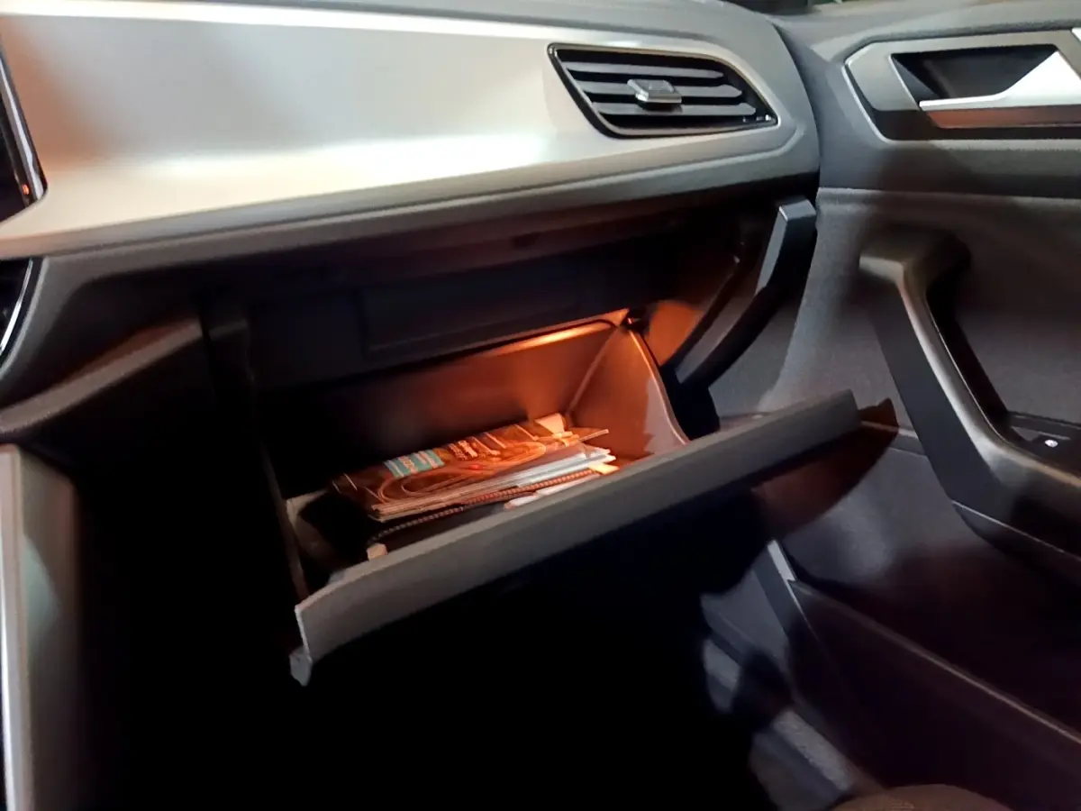 Gant de boîte à gants ouvert avec éclairage intérieur dans Volkswagen T-Roc gris foncé, vue côté passager.