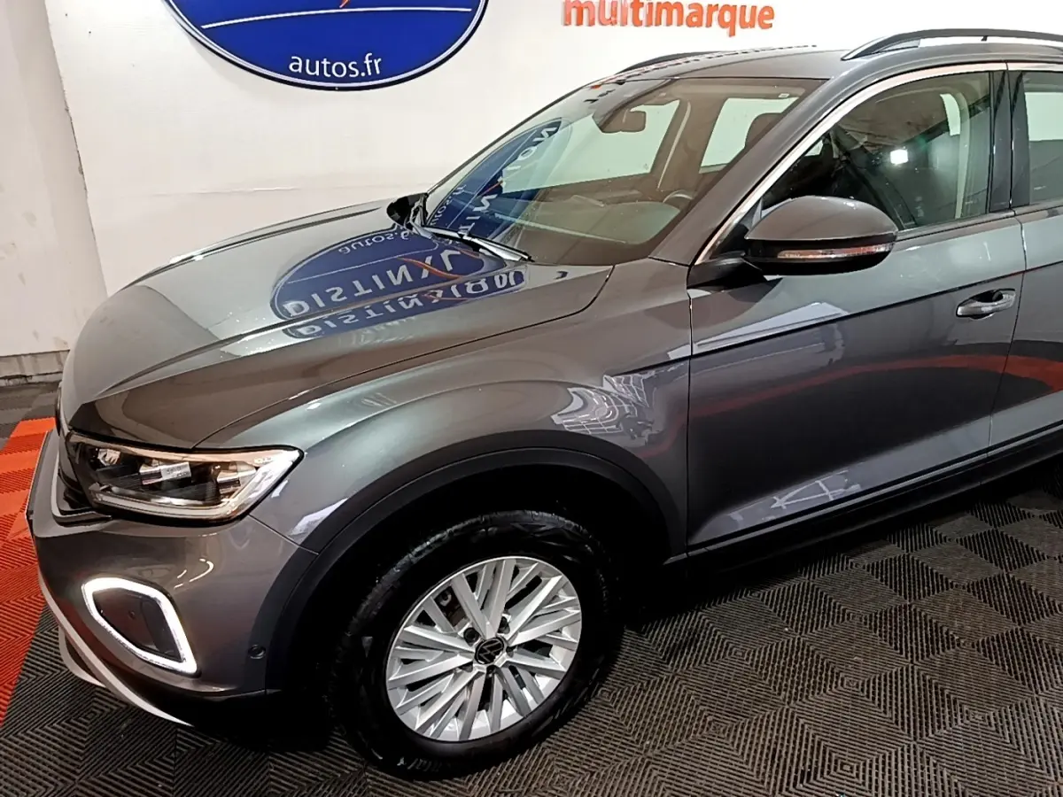 Vue 3/4 avant droit d’un Volkswagen T-Roc gris foncé avec feux LED et jantes alliage visibles.