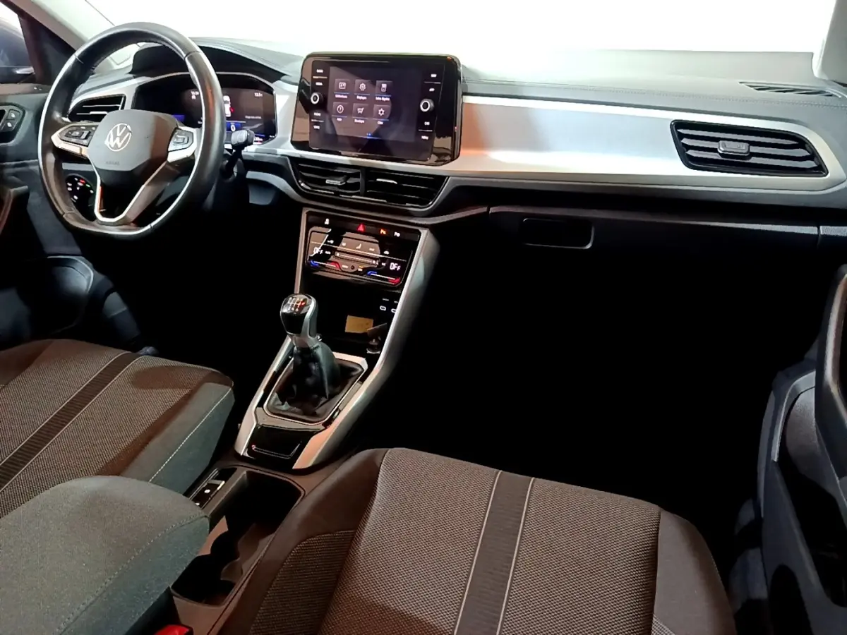 Intérieur Volkswagen T-Roc 1.0 TSI 2022 vu de face, tableau de bord noir avec écran tactile et levier de vitesse manuel.