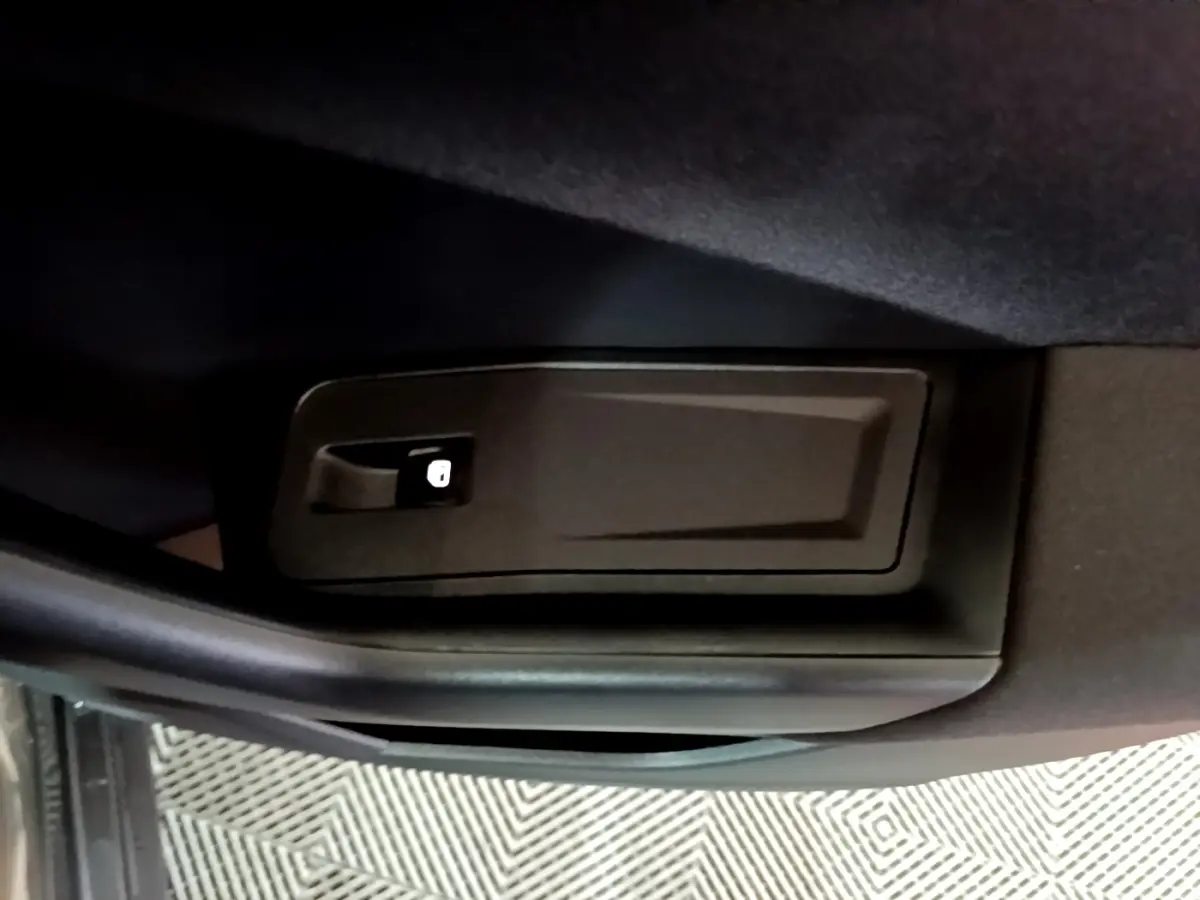 Détail du verrouillage intérieur de porte noir dans un Volkswagen T-Roc gris foncé, vue rapprochée.