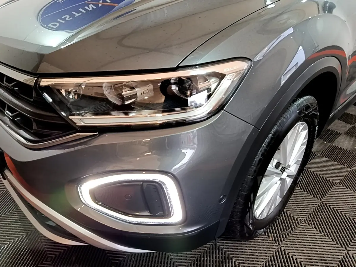 Gros plan sur l'avant droit du Volkswagen T-Roc gris foncé, mettant en valeur le phare LED et la roue.