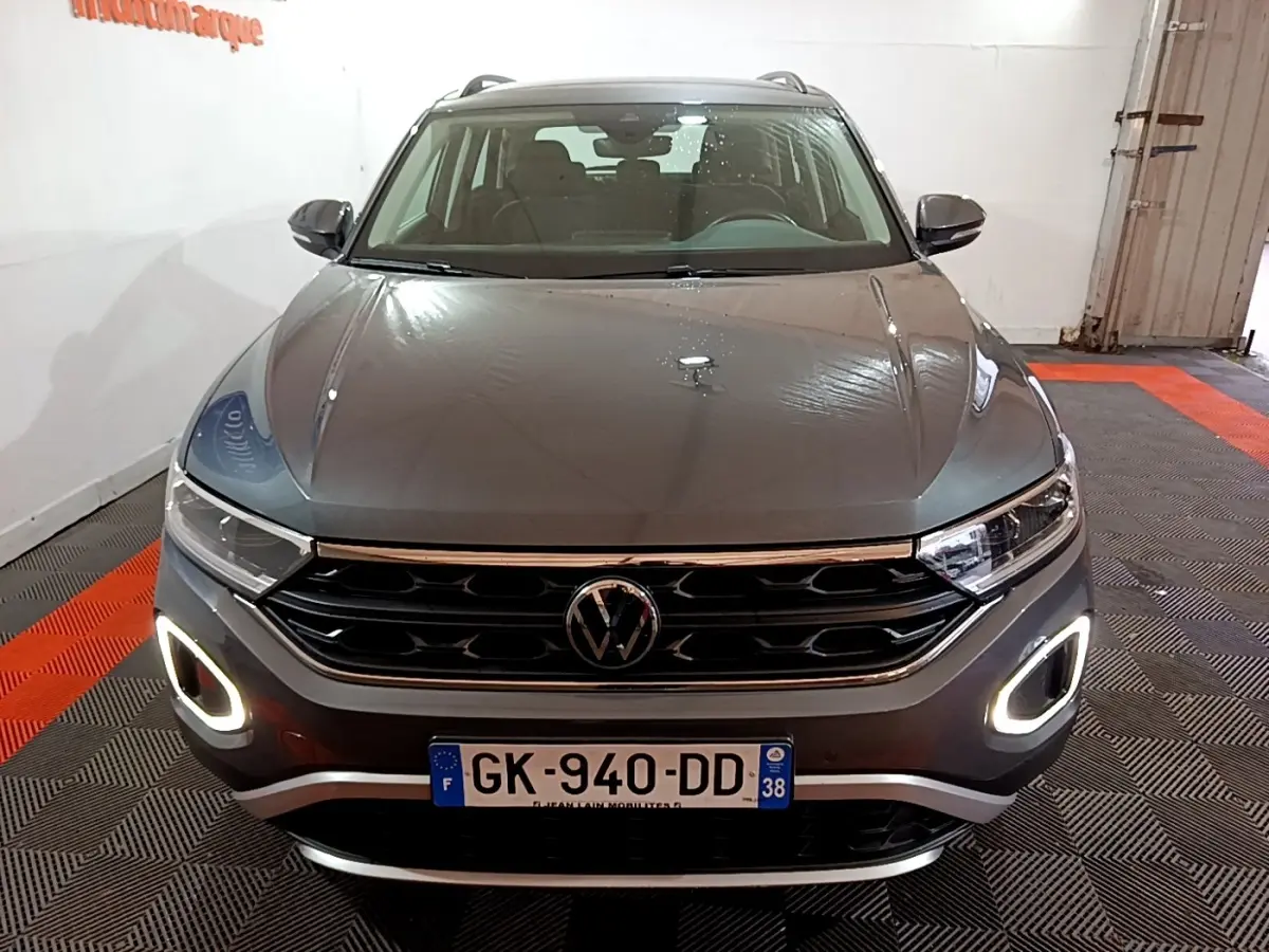 Vue avant d’un Volkswagen T-Roc gris foncé 2022 avec feux diurnes LED allumés dans un garage.
