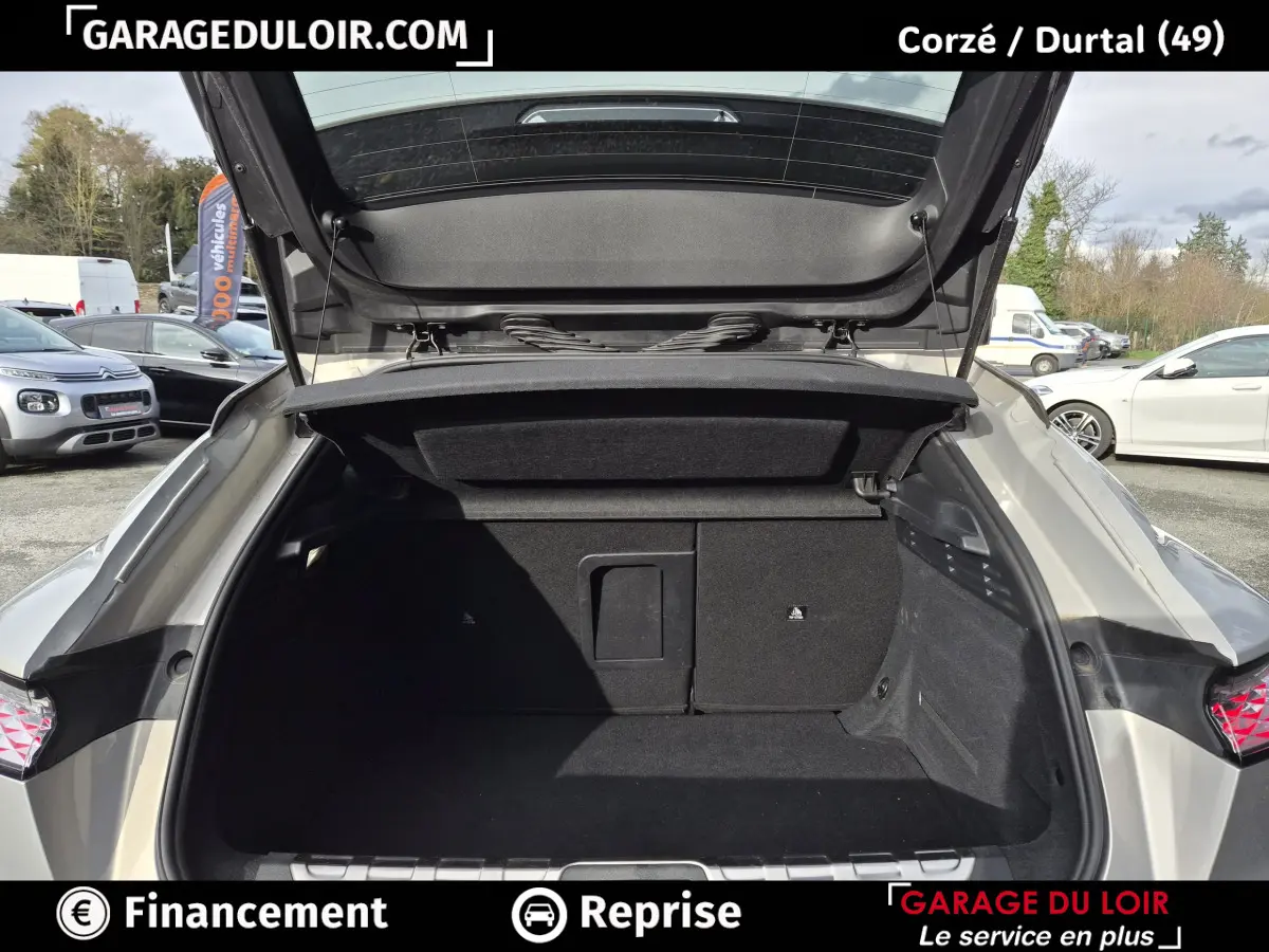 Coffre ouvert vu de l'arrière d'une DS4 beige 2024, montrant l'espace de chargement et la trappe à ski.