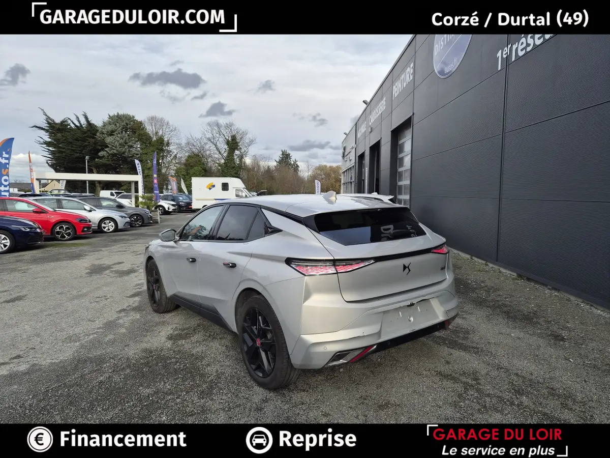 Vue 3/4 arrière droite d'une DS4 beige 2024 avec feux LED effilés et jantes noires sur parking extérieur.