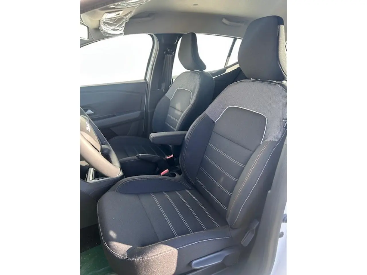 Vue intérieure côté gauche montrant les sièges avant noirs avec sellerie spécifique Stepway de la Dacia Sandero III blanche.