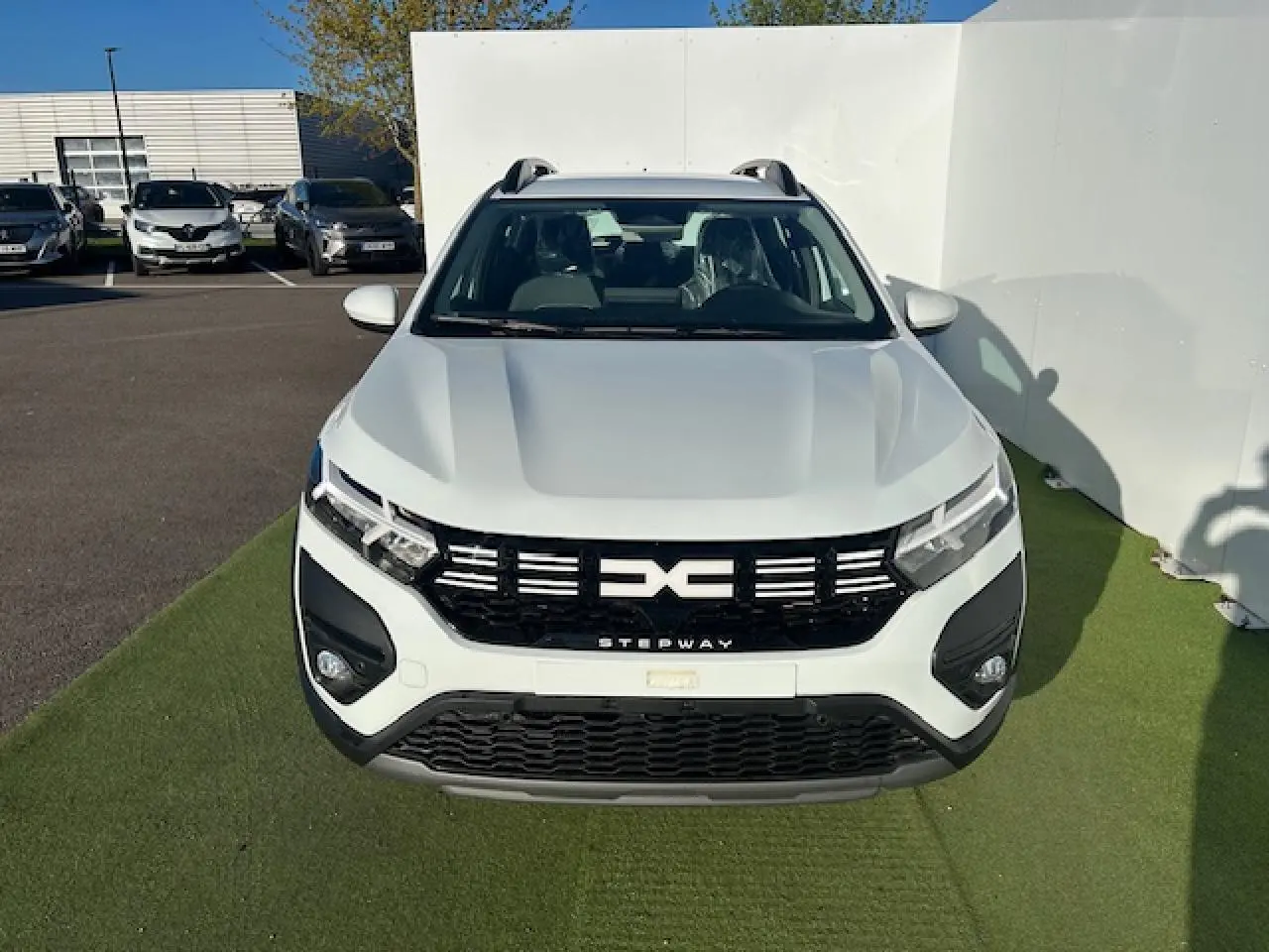 Vue avant d'une Dacia Sandero Stepway blanche Arctique avec calandre noire et signature lumineuse LED en Y.