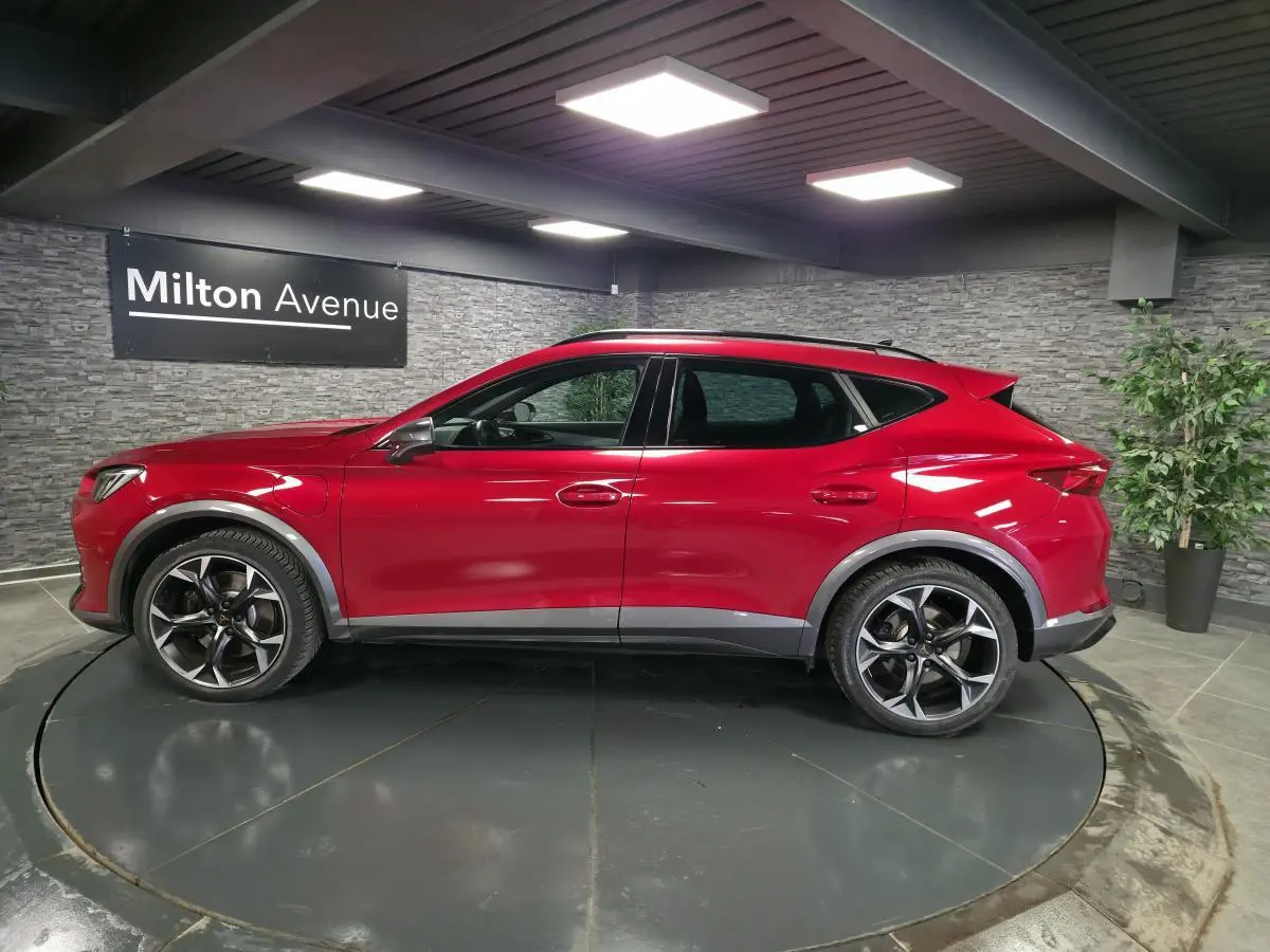 Vue de profil côté gauche d'un CUPRA Formentor 2024 rouge Désir avec jantes alliage noires et soubassements contrastants.
