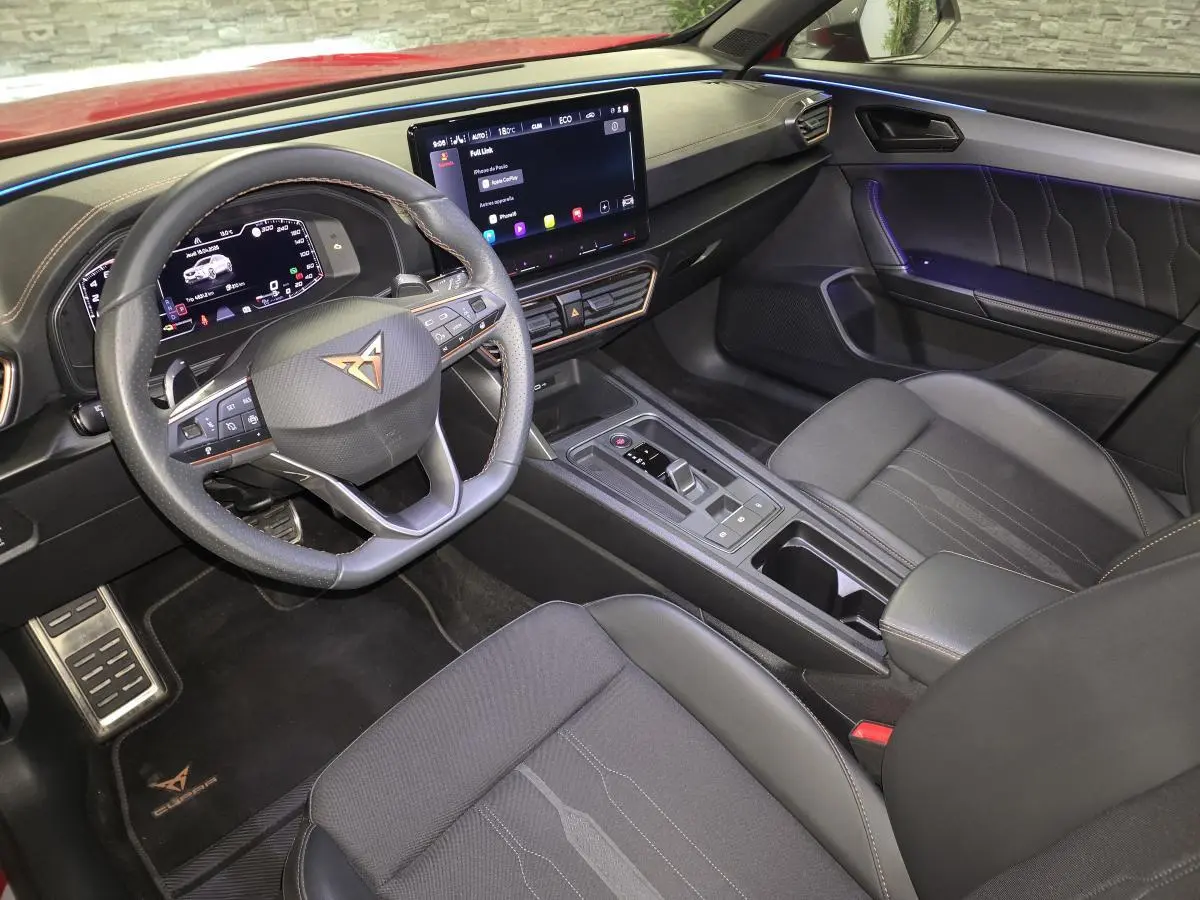 Vue intérieure côté conducteur du CUPRA Formentor 1.4 e-Hybrid 2024, avec volant sport, écran tactile et ambiance lumineuse violette.