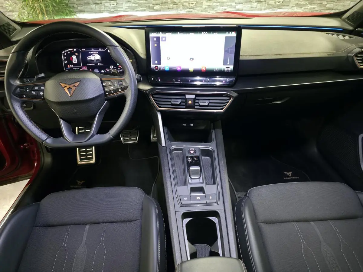 Intérieur avant du CUPRA Formentor rouge 2024, tableau de bord avec écran tactile 12", volant sport cuir et finitions Copper.