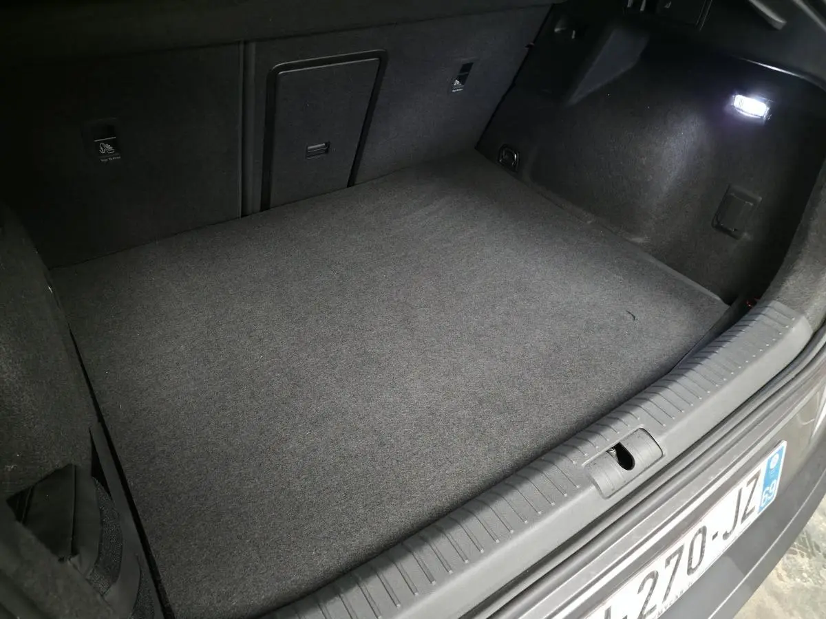 Coffre ouvert vu de l'arrière d'une CUPRA Formentor rouge, espace de chargement vide et éclairage intérieur allumé.
