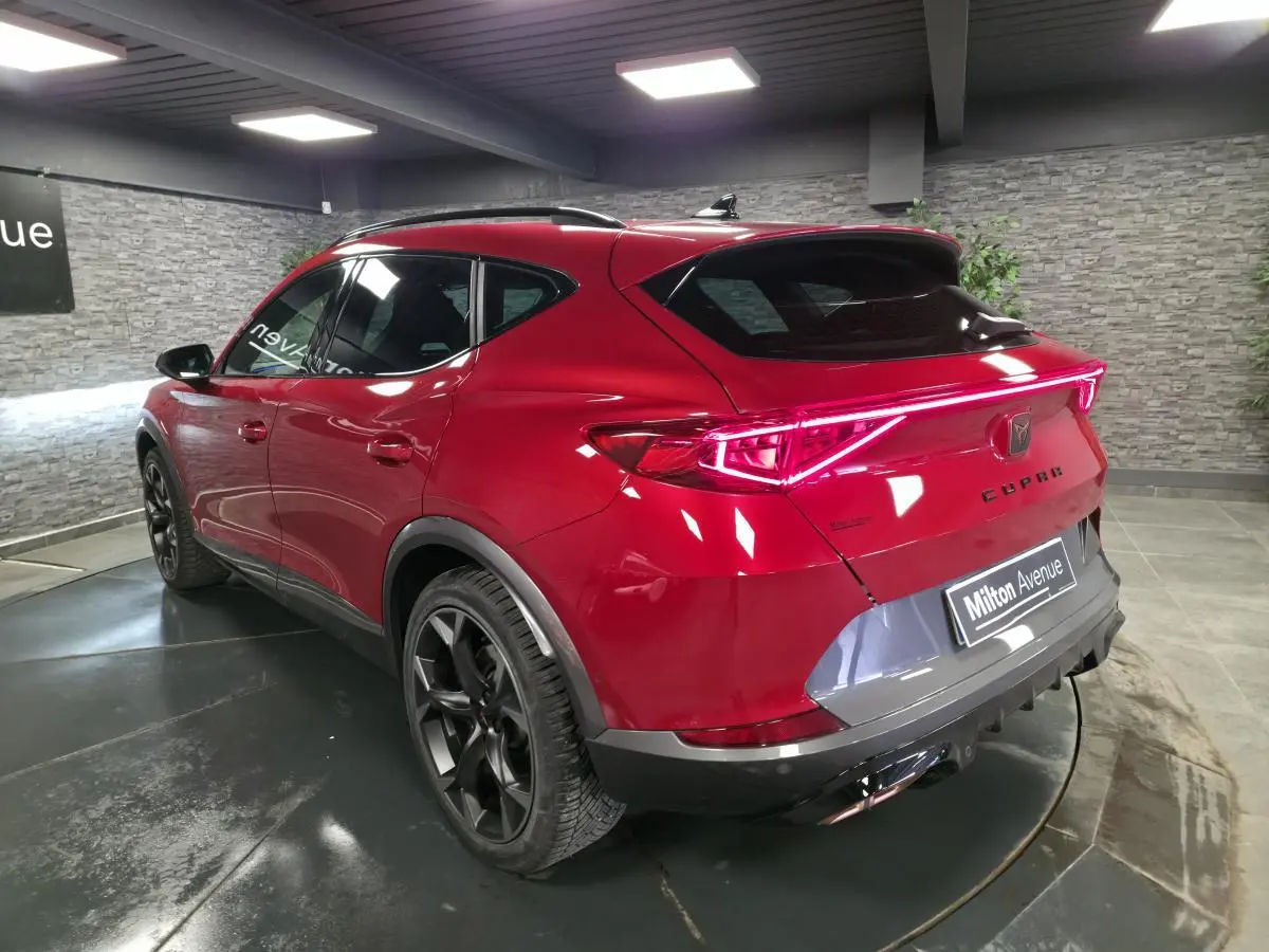 Vue 3/4 arrière droite du CUPRA Formentor rouge avec bandeau lumineux arrière et jantes alliage noires.