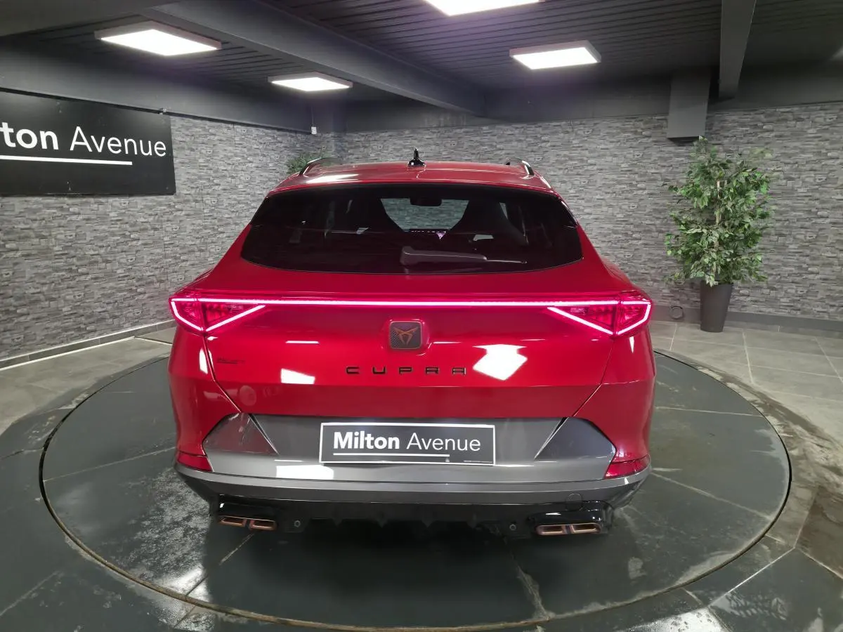 Vue arrière d'une CUPRA Formentor rouge avec bandeau LED Infinite Light et double sortie d'échappement copper stylisée.