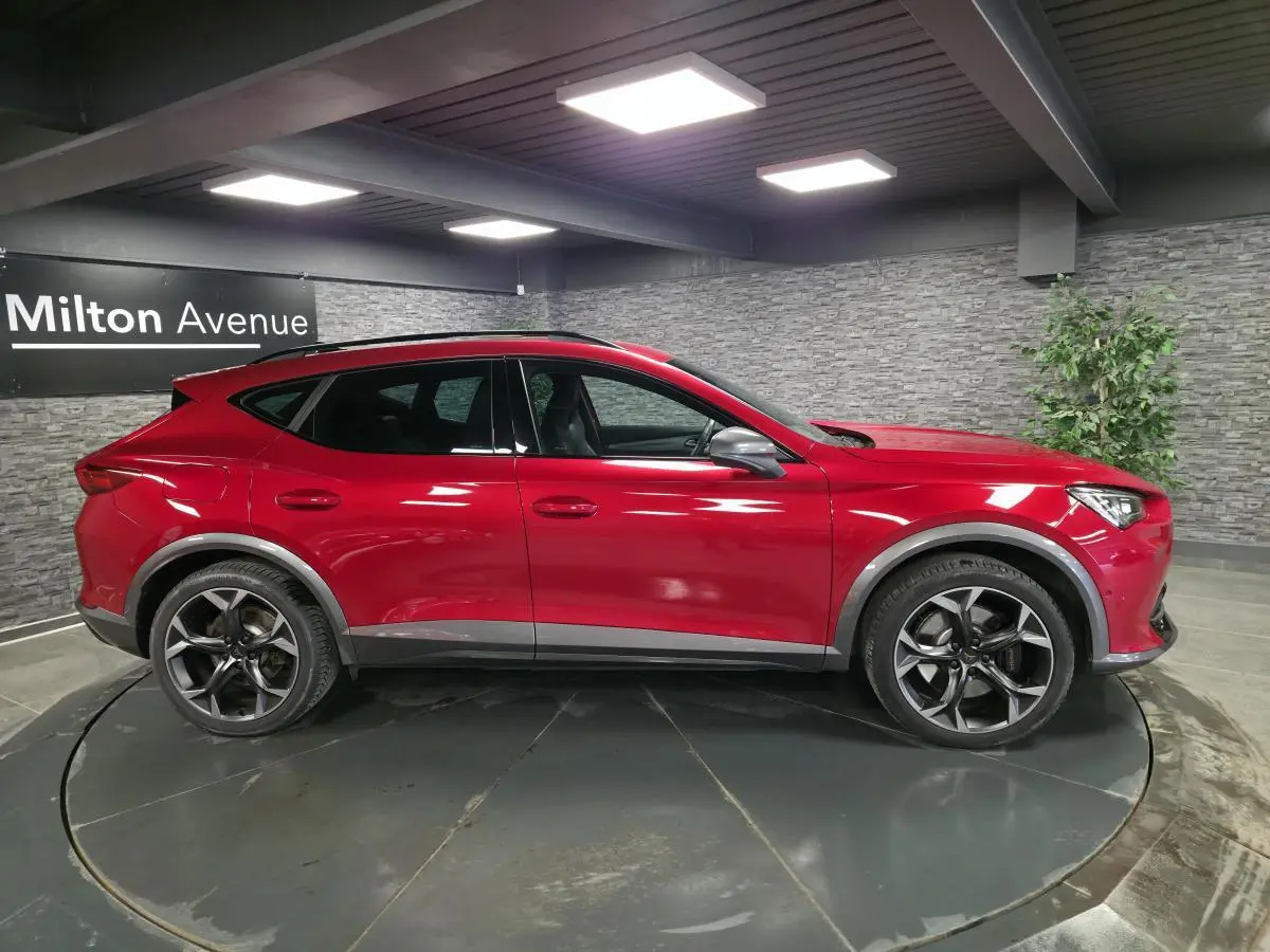 Vue de profil côté gauche du CUPRA Formentor 1.4 e-Hybrid rouge Désir avec jantes alliage 19 pouces et toit noir.