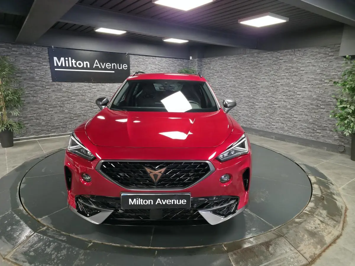 Vue avant d'une CUPRA Formentor rouge Désir 2024 avec calandre noire et logo cuivre, sur plateau tournant intérieur.