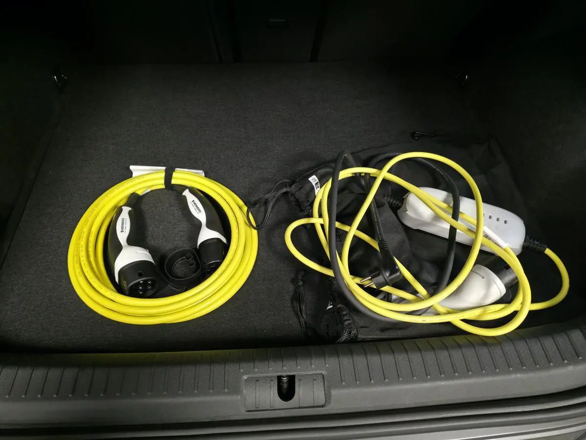 Vue du coffre d'un CUPRA Formentor rouge 2024 montrant les câbles de recharge jaune et noir rangés.