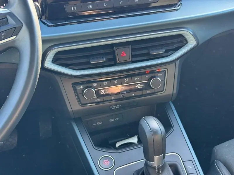 Vue intérieure centrée sur la console centrale et levier de vitesse cuir du SEAT Arona noir avec clim bi-zone et bouton start/stop.
